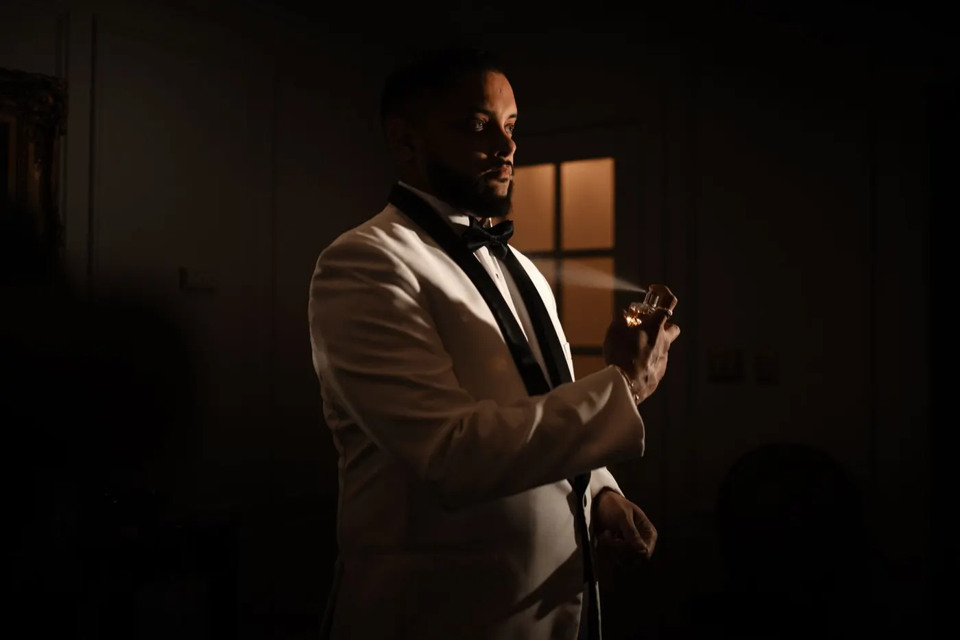 A man in a dinner jacket applying fragrance